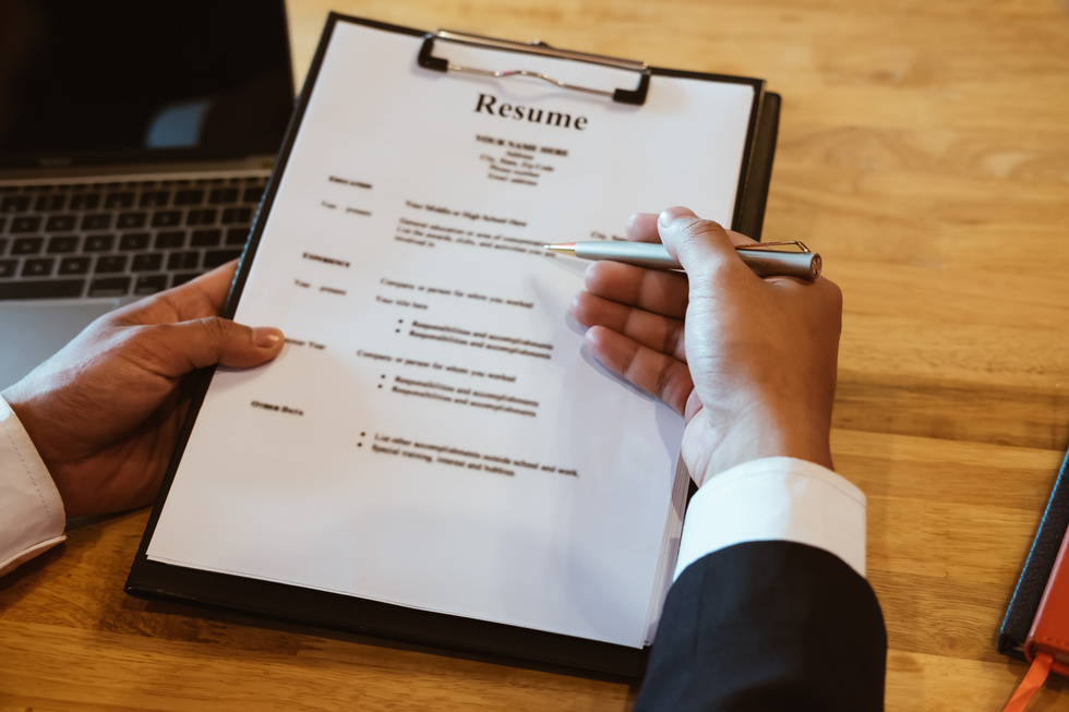 HR Manager Reviewing Resume Information on His Wooden Desk